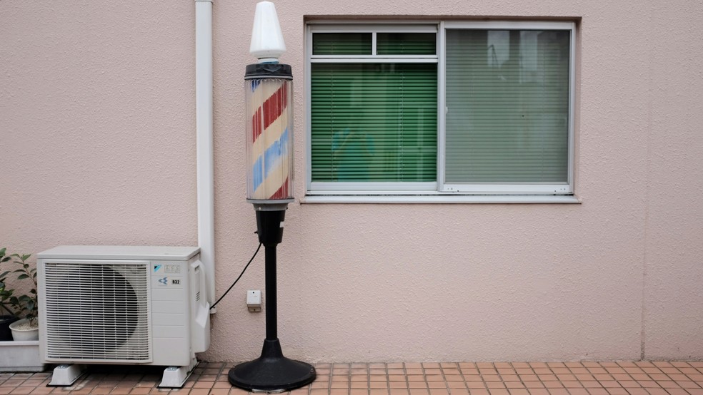 Condensadora de ar-condicionado posicionada em varanda com janela de cortinas verdes — Foto: Reprodução/Unsplash (Mak)