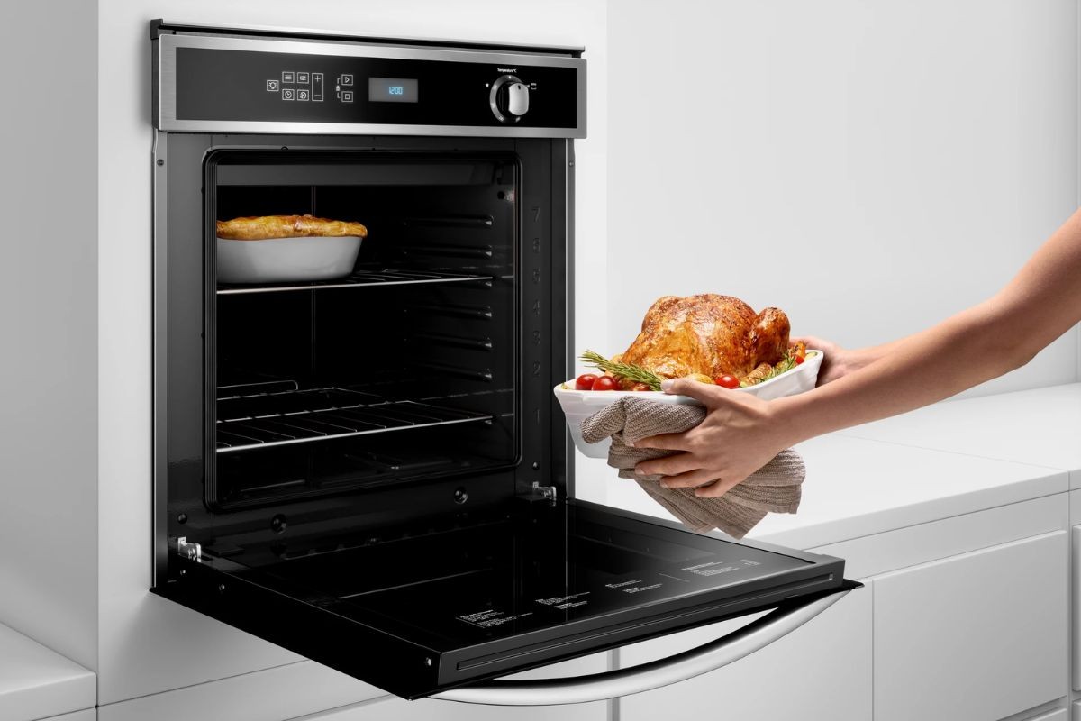 Retirando-um-frango-assado-do-forno-eletrico-embutido Retirando-um-frango-assado-do-forno-eletrico-embutido